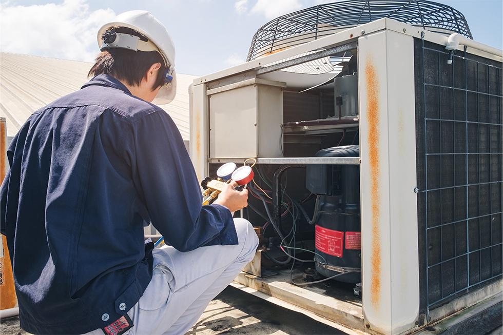 Image of an HVAC worker working on a air conditioner.
